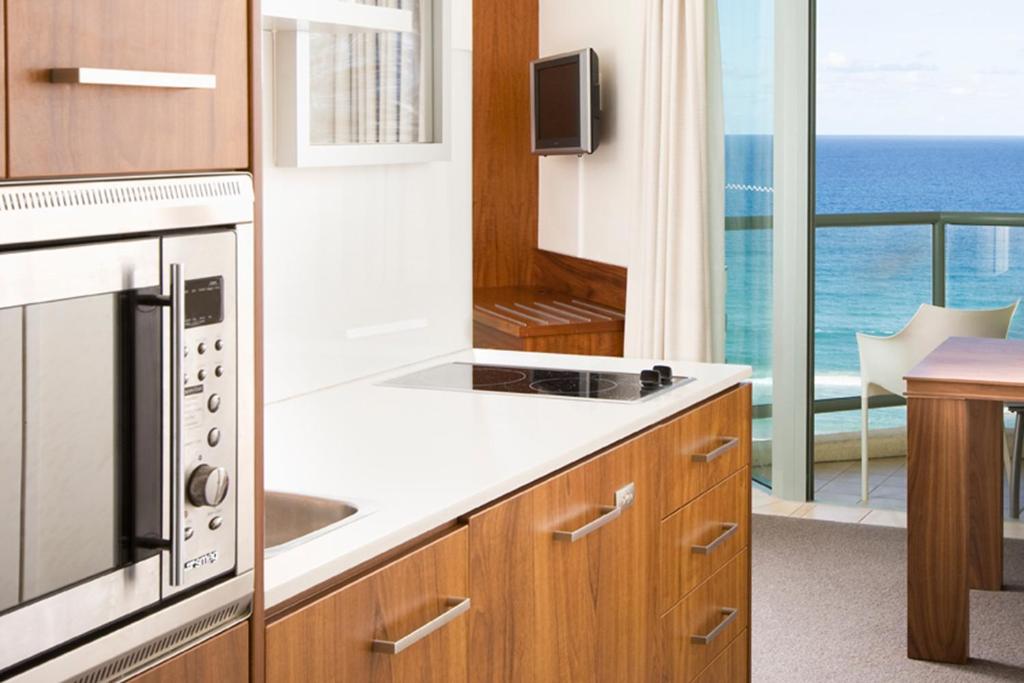 a kitchen with a sink and a microwave at Mantra Legends Hotel in Gold Coast