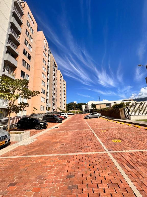 a red brick road with cars parked in a parking lot at Apto acogedor en Ibague in Ibagué