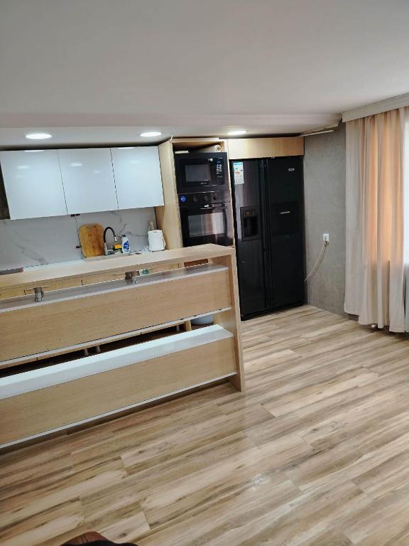a kitchen with wooden floors and a kitchen with black appliances at gulelebi in Tʼianetʼi