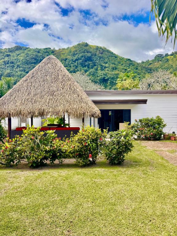 a house with a straw roof and some plants at Vanakea Beach House, accès privé plage PK18 in Punaauia