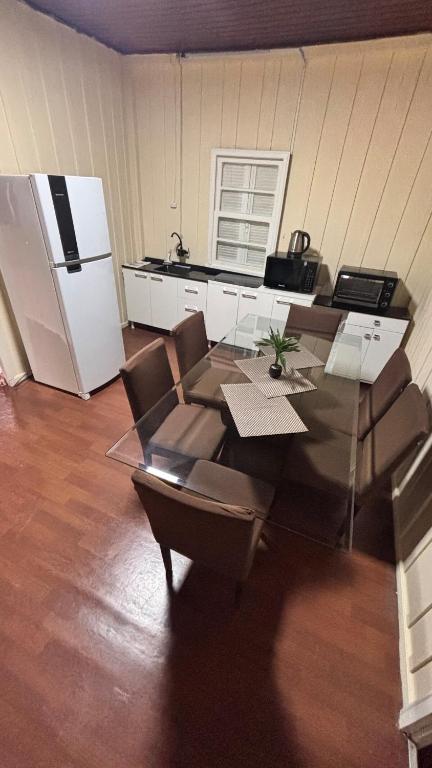 a kitchen with a glass table and chairs and a refrigerator at Casa no Centro in Campo Largo