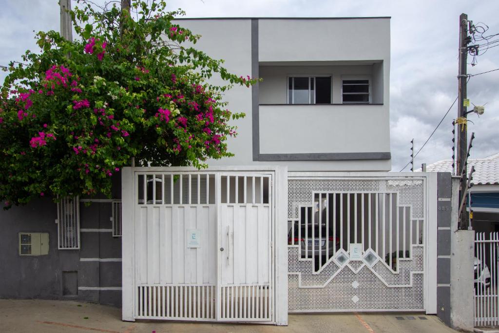 a white house with a white gate and a tree at LOFT NOVO CONFORTÁVEL in Sorocaba