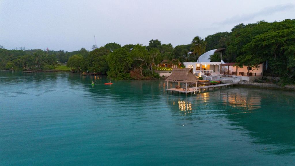 a view of a river with a building on the shore at GlampCalar lagoon Front Bungalows in Rancho Bacalar
