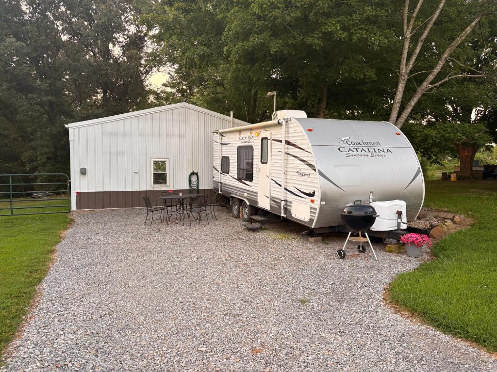 an rv parked next to a table and a grill at Cozy Camper in Creal Springs