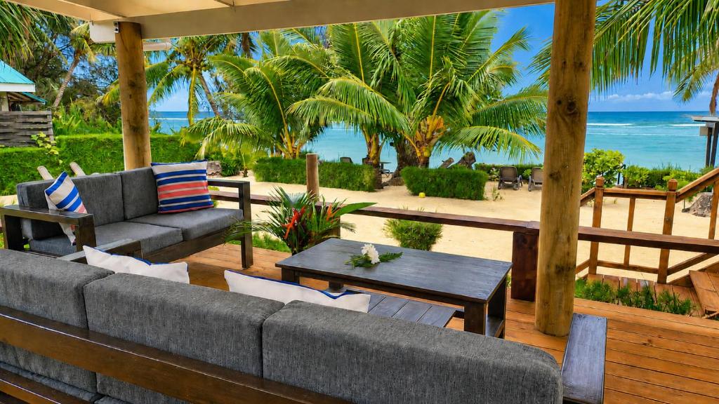 a patio with a couch and a table and the beach at Sunset Palms Rarotonga in Rarotonga