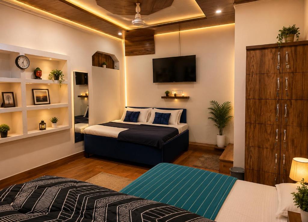 a bedroom with two beds and a tv on the wall at RadhaRaman StayInn in Mathura