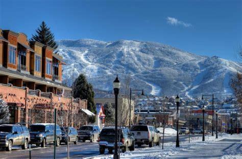 a snowy street with cars parked in front of a mountain at TIMBER TRAIL RETREAT in Steamboat Springs