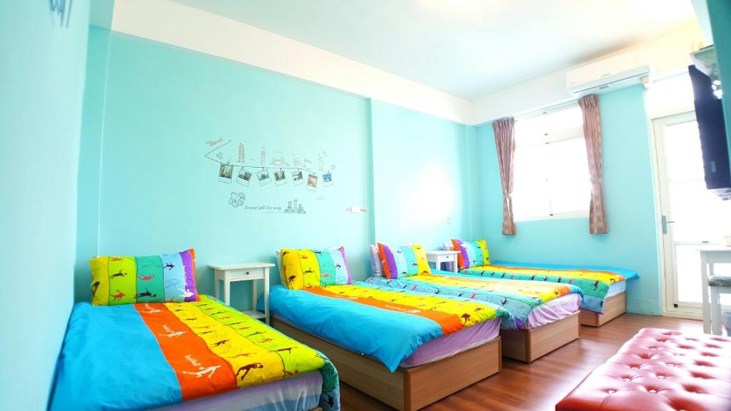 3 camas en una habitación con paredes azules en 站前海民宿 en Hualien