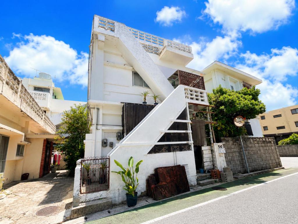 a white house with a staircase in front of it at おきなわ民泊海族 in Okinawa City
