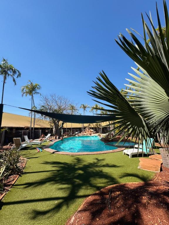 a large swimming pool with people sitting around it at Roebuck Bay Backpackers in Broome