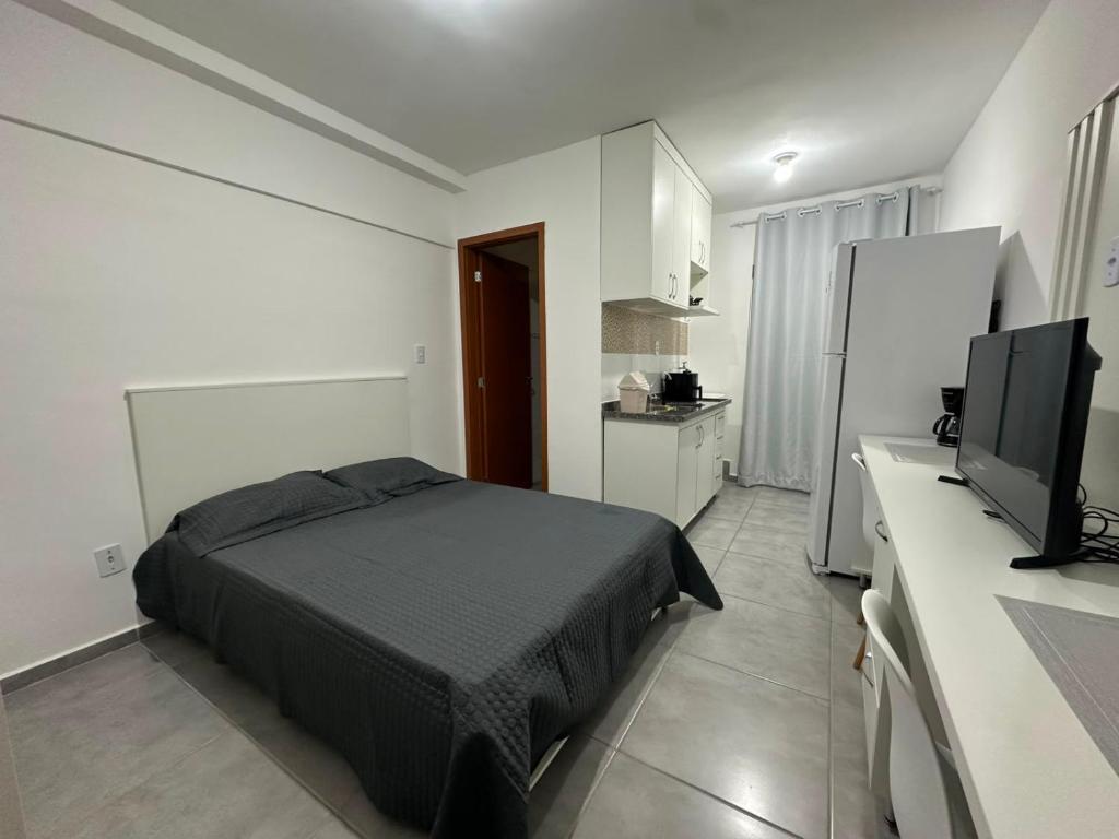 a bedroom with a bed and a flat screen tv at Studio Blanc - Espaço e conforto com uma vista incrivel in Barbacena