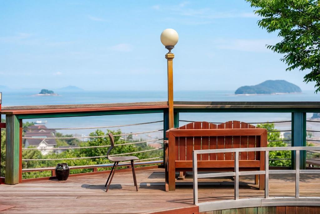 a bench and a lamp on a deck with a view of the ocean at Muuido Haedungsil Pension in Incheon