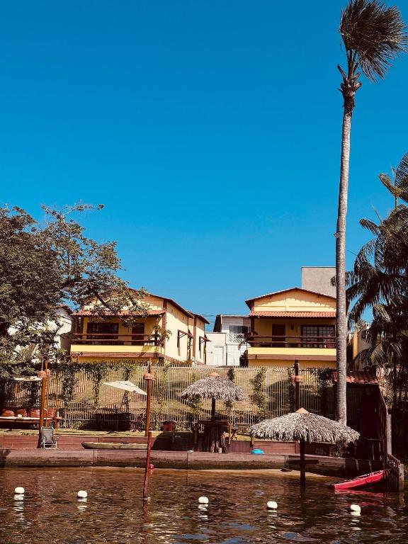 a palm tree and a building with umbrellas in the water at Vila dos Poetas in Barreirinhas