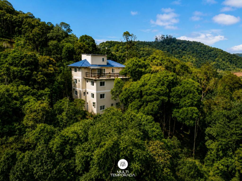a building on the side of a hill with trees at Pousada Casa do Reiki - Rancho Queimado/SC in Rancho Queimado