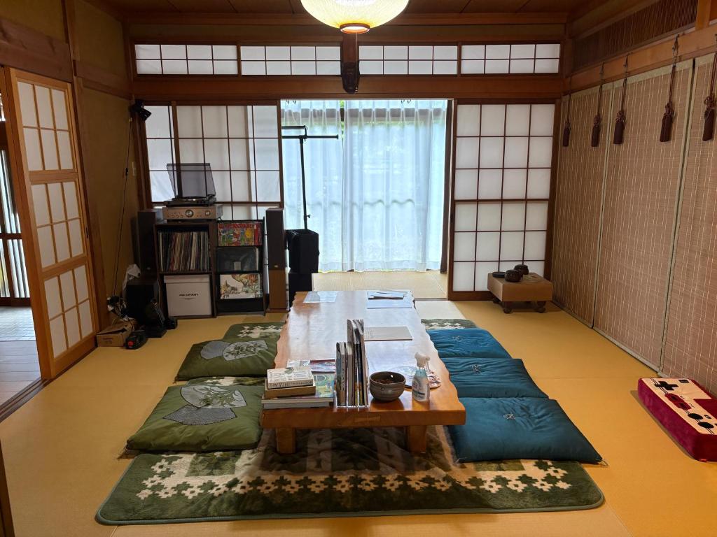 a living room with a table and a large rug at Yamaneko Lodge in Gujo