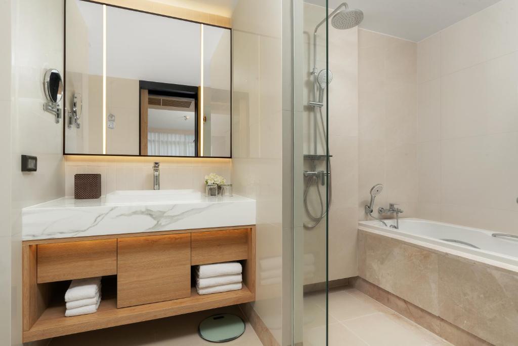 A bright bathroom with a double vanity, glass shower and separate soaking tub.