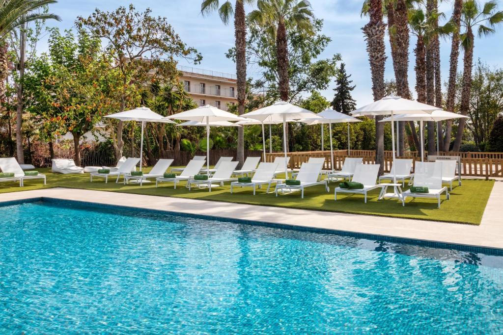 a pool with lounge chairs and umbrellas at Meliá Lloret de Mar in Lloret de Mar