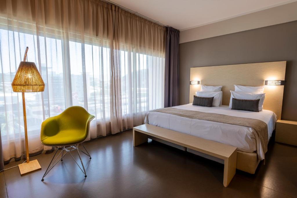 a hotel room with a bed and a yellow chair at Hôtel du Centre Appart hôtel Business avec Parking Gratuit à Nouméa in Noumea