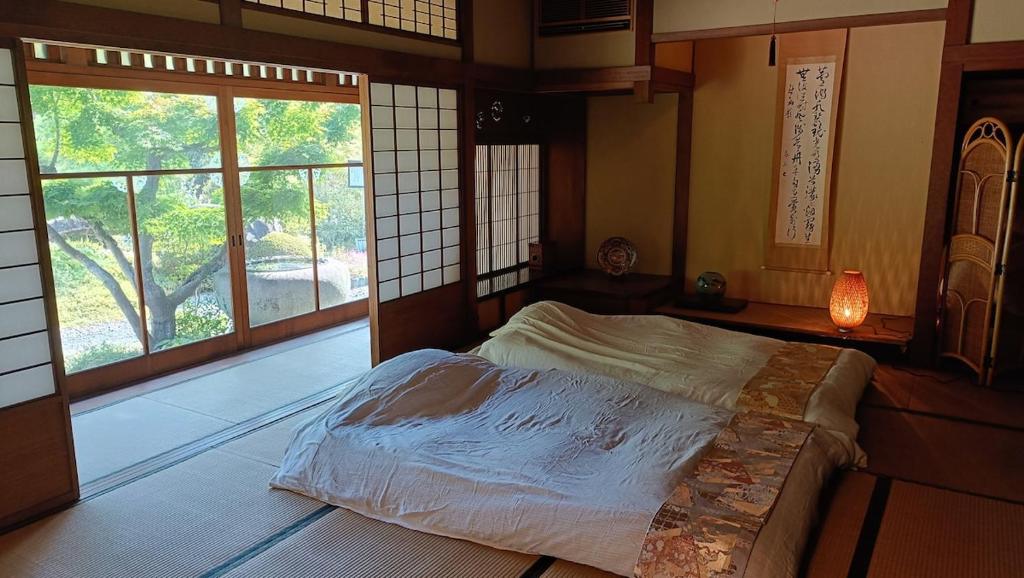a bedroom with a bed in a room with windows at 茶室山谷庵 in Gero