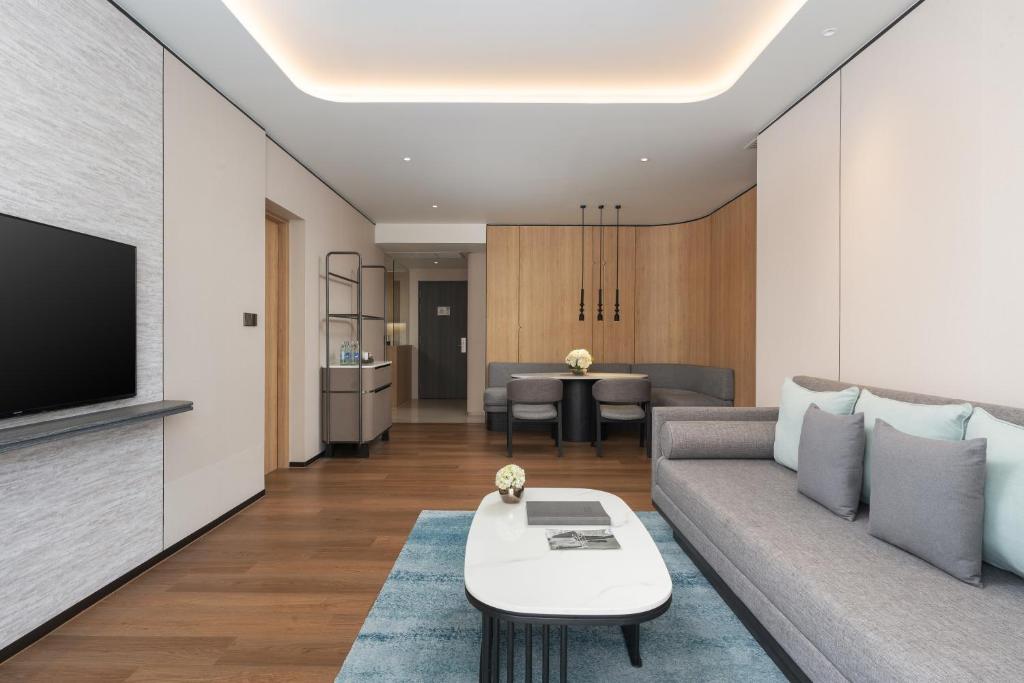 A long open-plan living area with sofa seating, dining space and a wall-mounted television.