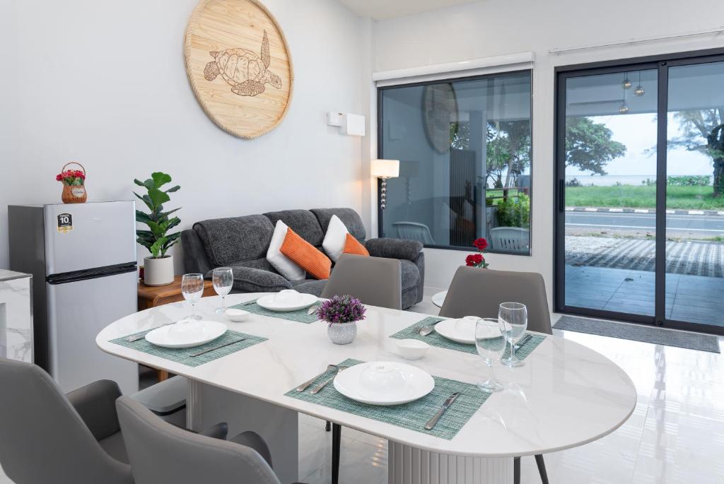 a white dining room with a white table and chairs at Turtle Tales-Tao Kra in Thai Muang