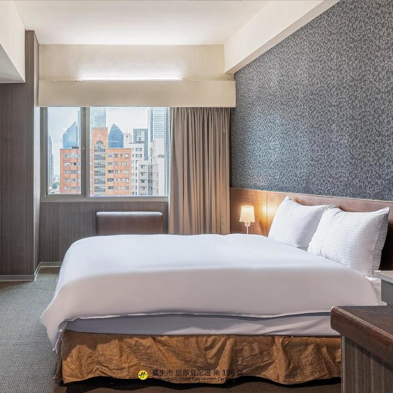 a bedroom with a large white bed and a window at The Galerie Hotel in Taichung