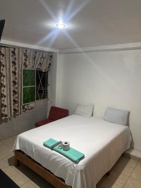 a bedroom with a white bed and a red chair at Hospedaje Lima Suite in Piura