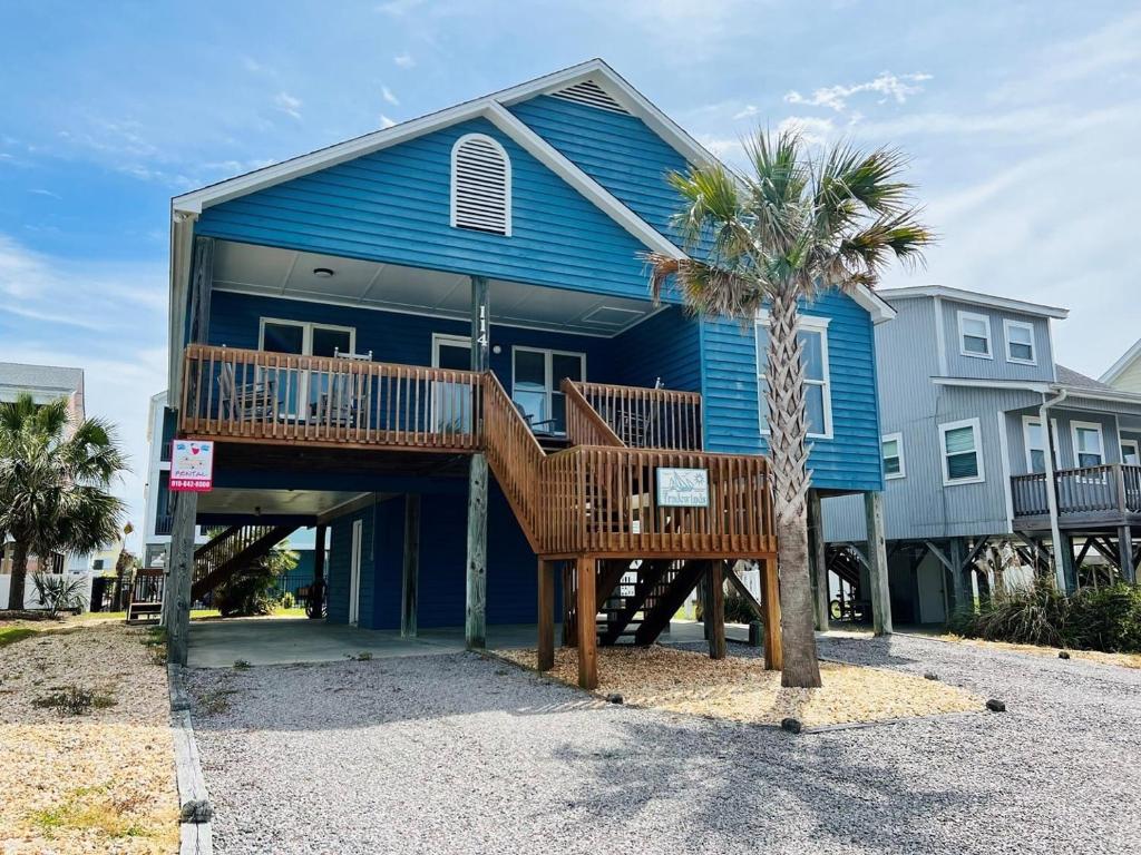 a blue house with a palm tree in front of it at Tradewinds in Holden Beach