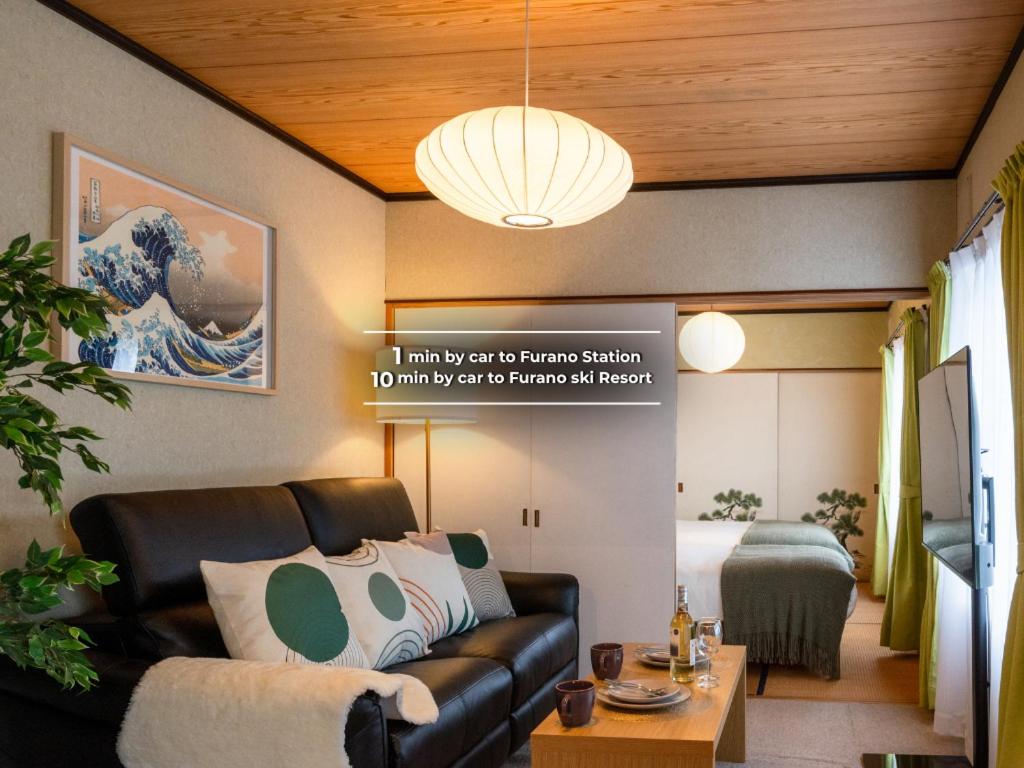 a living room with a black couch and a chandelier at Powder Snow 粉雪 in Furano
