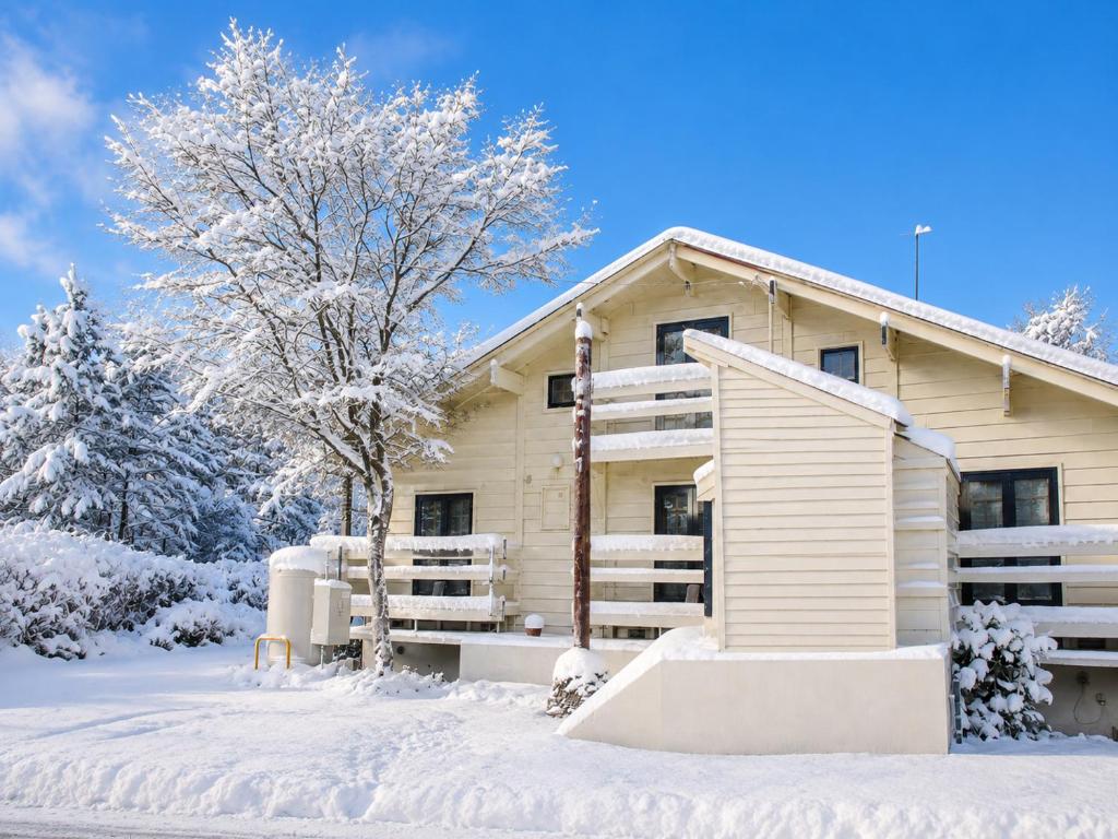 a house covered in snow in front at Maple House Backpackers in Iiyama