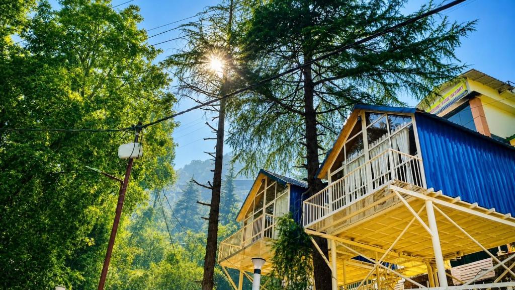 a house in the woods with a blue building at Treehouse by the lake in Bhīm Tāl