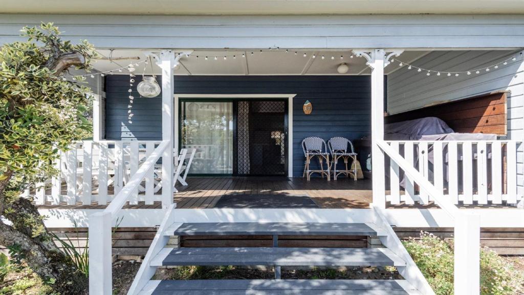 a porch with a bed and chairs on a house at Wooli House in Wooli