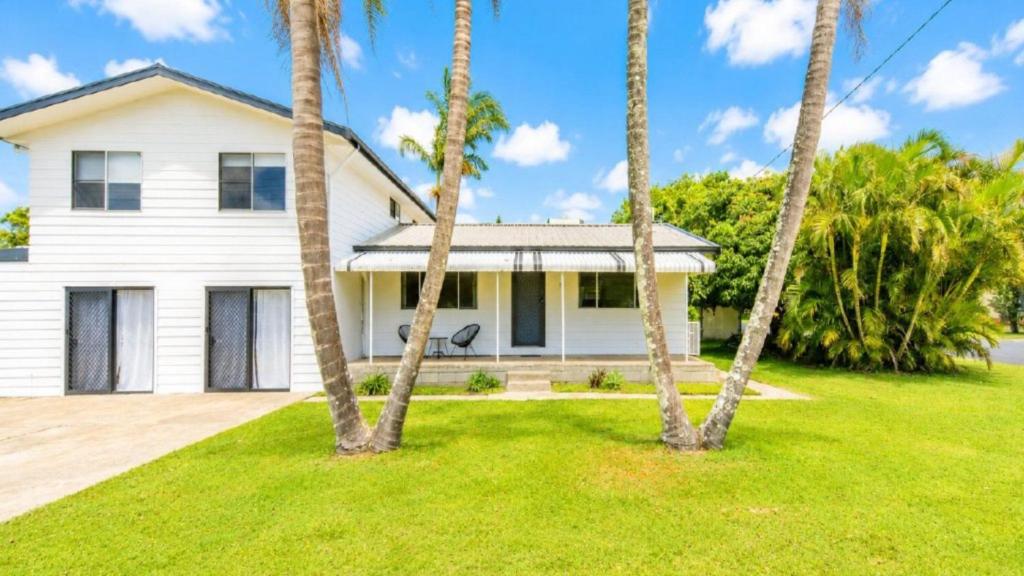 a white house with palm trees in front of it at Twin Palms Retreat in Wooli