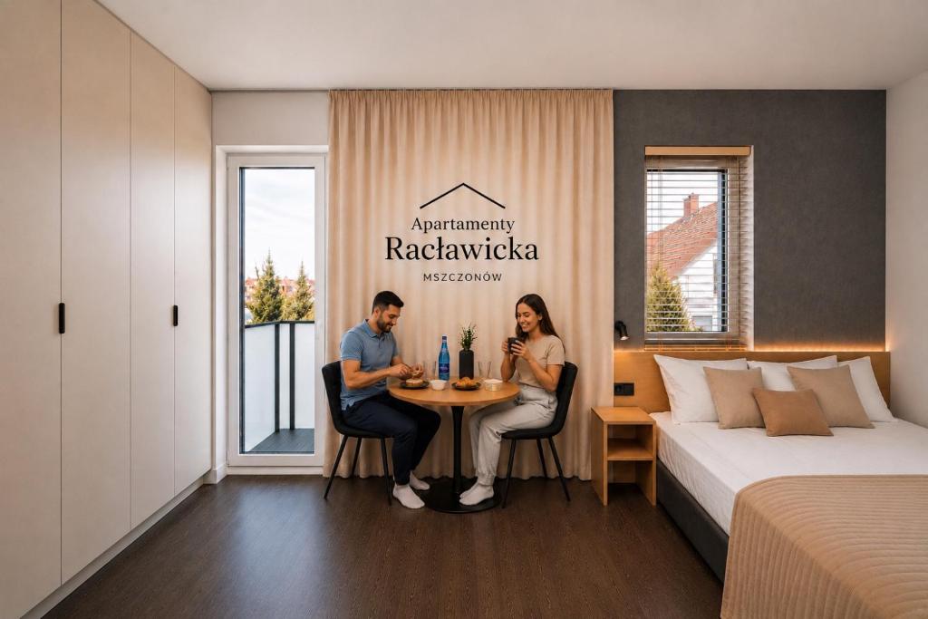 a man and woman sitting at a table in a hotel room at Apartamenty Racławicka Mszczonów in Mszczonów