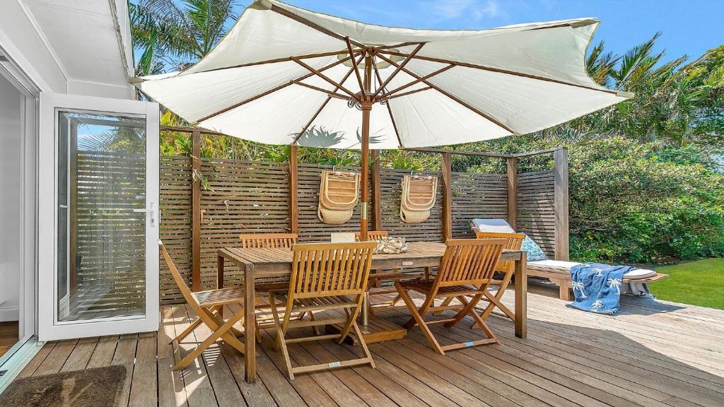 a wooden table and chairs with an umbrella on a deck at Sea Legs in Wooli