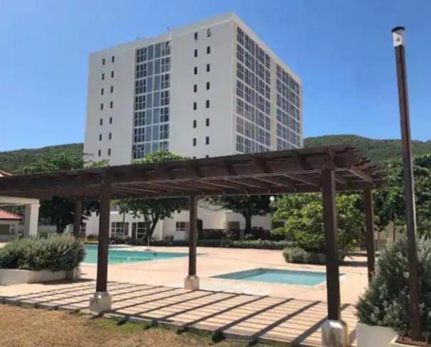 a building with a pool and a pavilion in front of a building at The Grand suite in Portmore