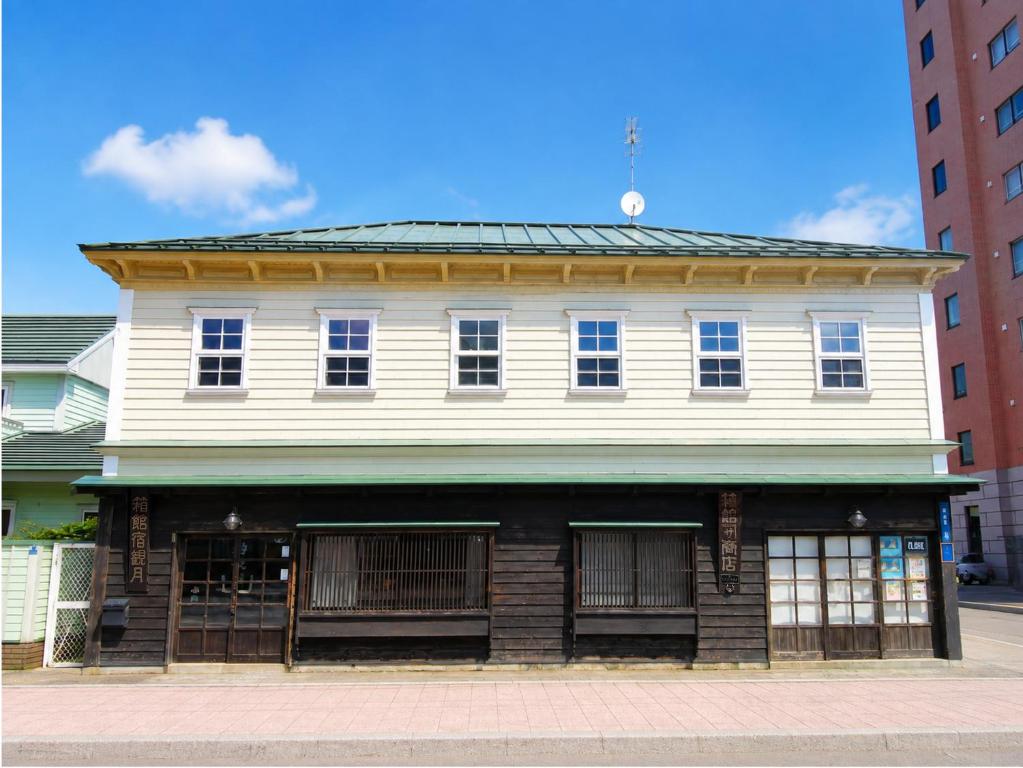 an old white building with windows on a street at 金森赤レンガ倉庫徒歩すぐ 伝統建築リノベ貸切 最大8名 最新設備 in Hakodate