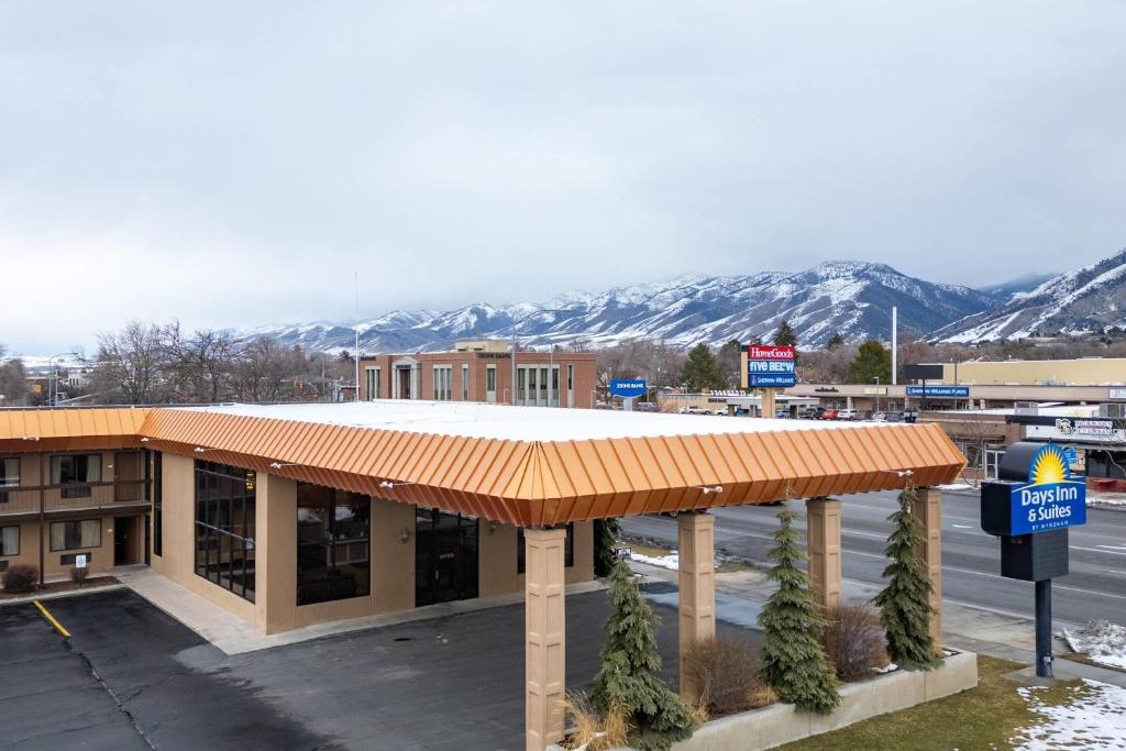 a building with an orange roof with mountains in the background at Days Inn & Suites by Wyndham Logan in Logan