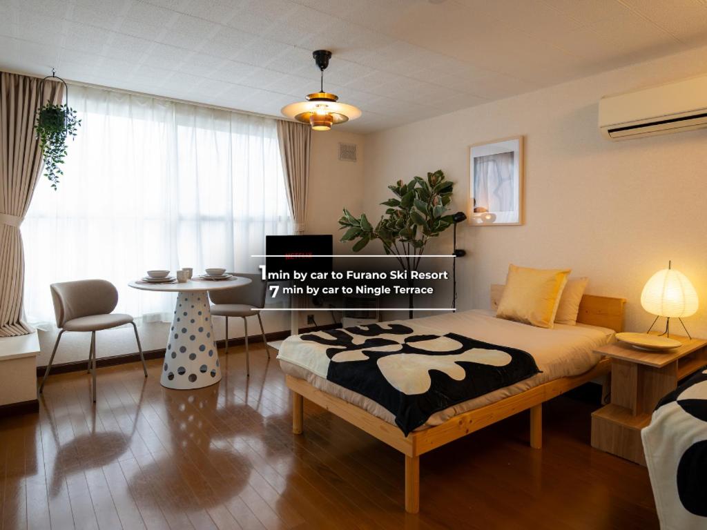 a bedroom with a bed and a table in it at BREEZE furano 山彦 霧 in Shimo-furano