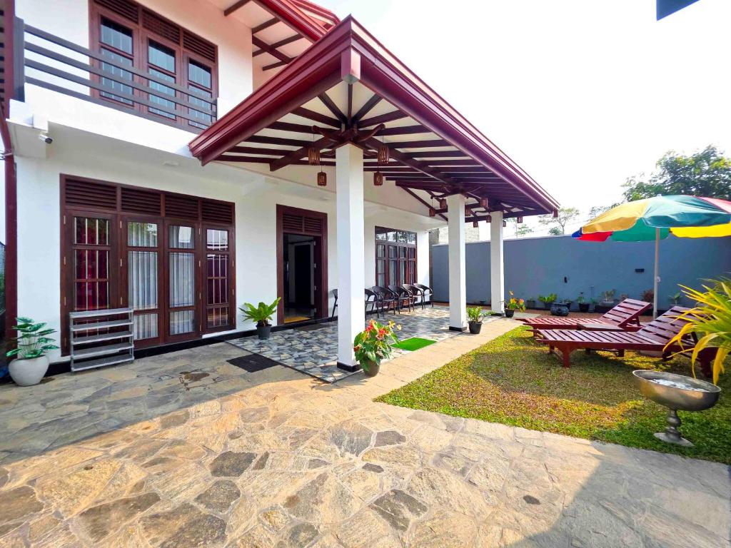 a patio of a house with a bench and an umbrella at Dishan Green Retreat in Ambalangoda