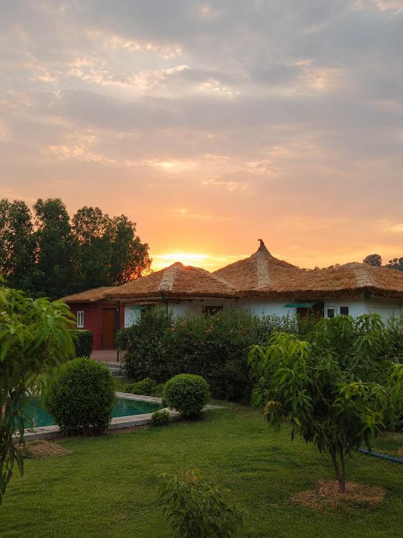 a house with a pool and a sunset in the background at Homestead thapli in Pinjaur