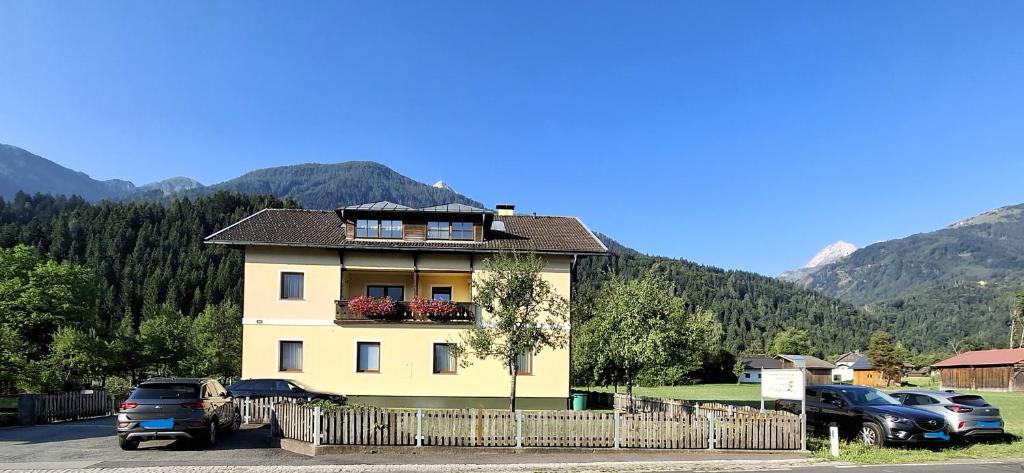a yellow house with cars parked in a parking lot at Ferienwohnungen Berger in Kötschach
