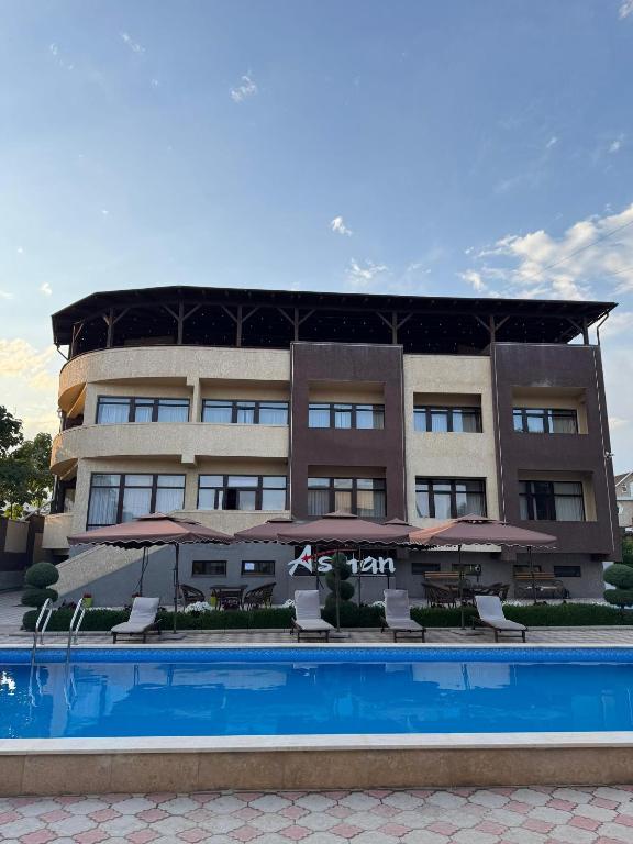 a building with a pool and chairs and umbrellas at Asman Hotel in Bosteri