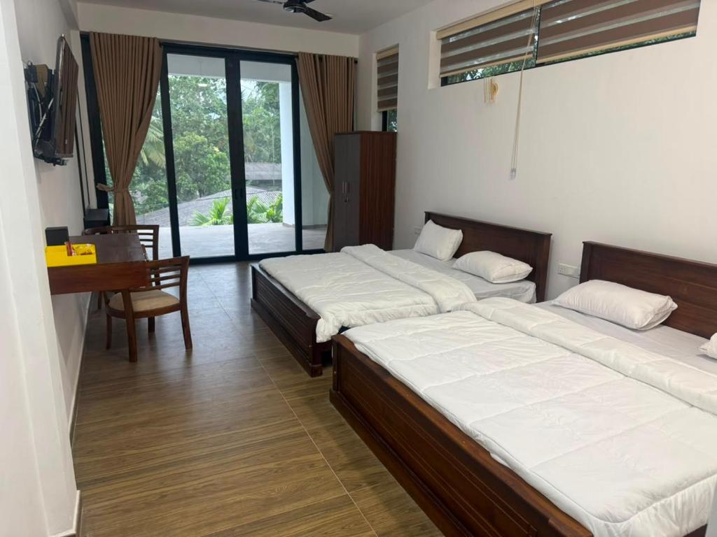 ein Schlafzimmer mit zwei Betten, einem Tisch und einem Schreibtisch in der Unterkunft 32AW hotel in Matale