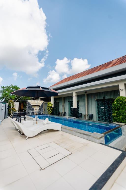 a patio with an umbrella and a swimming pool at V Canggu Dormitory in Canggu