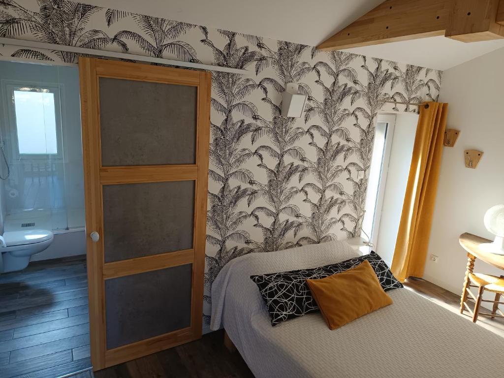 a bedroom with a bed and a wall with wallpaper at Logement entier 3 pièces et terrasse in Mazières-en-Gâtine