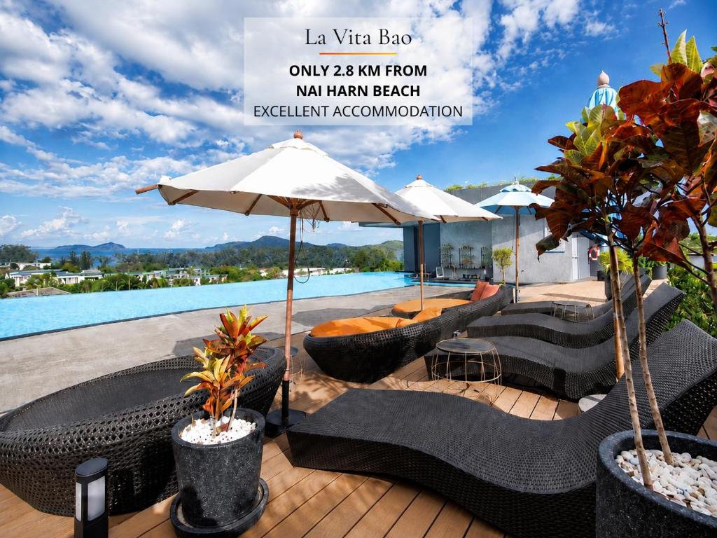 a patio with chairs and an umbrella and a pool at La Vita Bao in Phuket