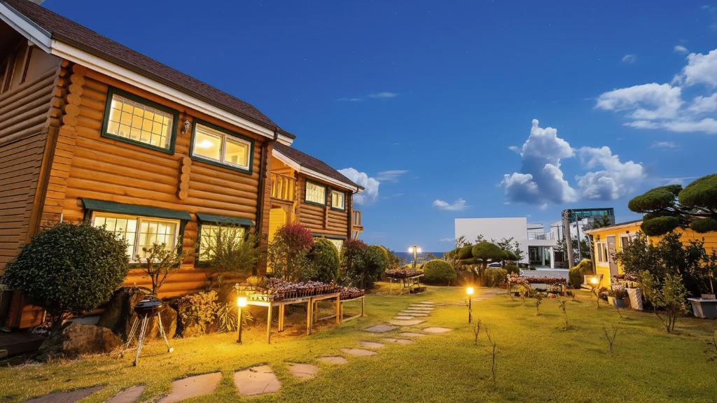 a wooden house with a yard in front of it at Seogwipo Neulbada Pet Pension in Seogwipo