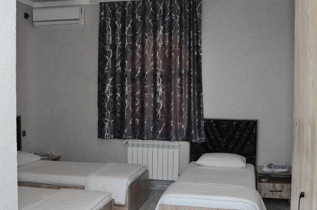 a room with three beds and a window with curtains at Seki Qonaq Evi in Sheki