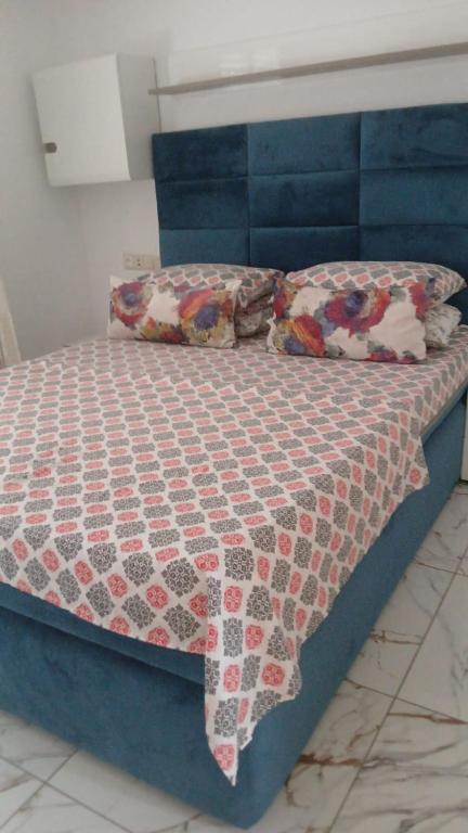 a bed with a blue head board with a quilt on it at Appart Cosy in Fnidek